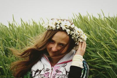 Portrait of woman wearing flowers while sitting against plants