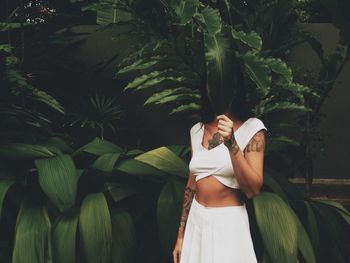 Woman holding umbrella standing by plants