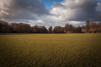 View of trees on field against cloudy sky