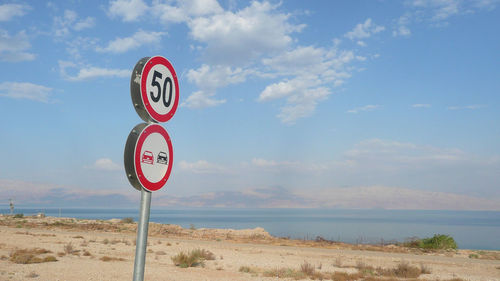 Speed limit sign at beach against sky