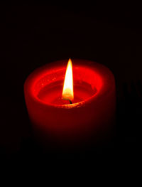 Close-up of lit candle against black background