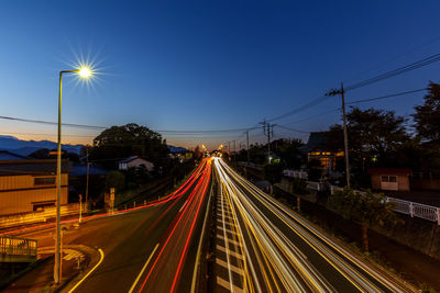 Light trails on street in city against sky at night