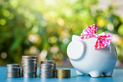 Close-up of piggy bank with stacked coins on table