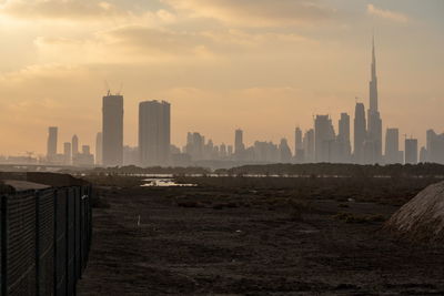 Modern buildings in city against sky during sunset