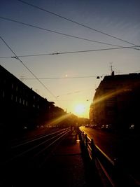 Road amidst silhouette bridge against sky at sunset