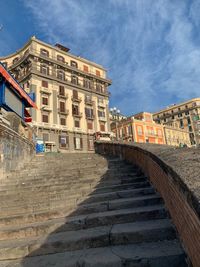 Low angle view of steps amidst buildings against sky