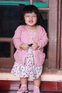Full length of cute girl standing against wall