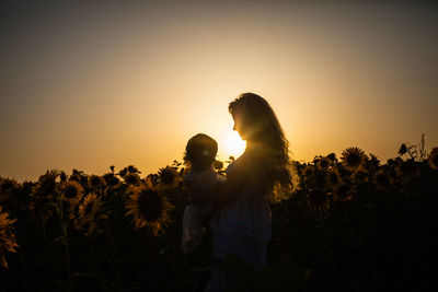 Silhouette woman standing on field against sky during sunset