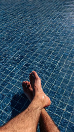 Low section of man relaxing in swimming pool