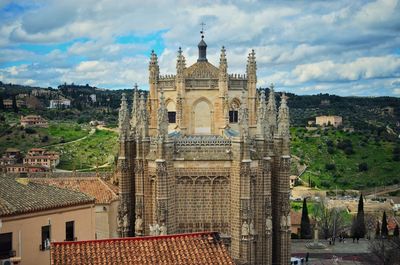 Buildings and church against cloudy sky