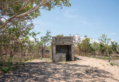 Old ruin amidst trees on field against sky