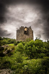 Low angle view of abandoned building against cloudy sky