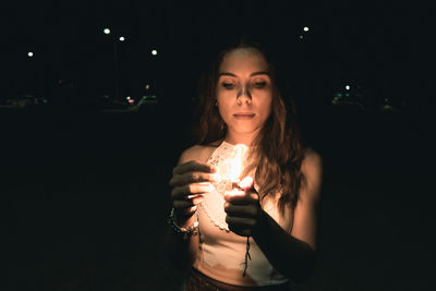 Portrait of a young woman drinking glass at night