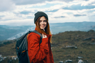 Portrait of smiling young woman standing against sky