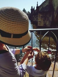 High angle view of woman with boy hanging padlock on railing