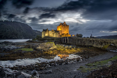 View of castle on cliff against cloudy sky