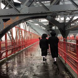 Rear view of people walking on bridge