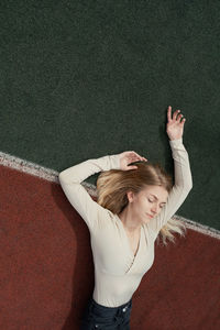 Full length of woman with arms raised standing on field