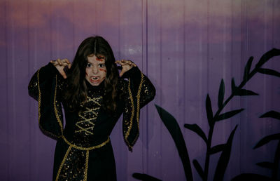Portrait of one girl in a witch dress with makeup with scars on her face and making a scary grimace 