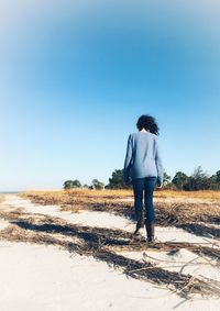 Rear view of man standing on field against clear sky