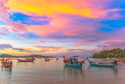 Boats moored in sea against sky during sunset