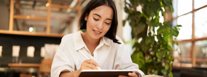 Portrait of young woman using mobile phone while sitting in cafe