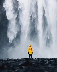 Rear view of woman standing against waterfall