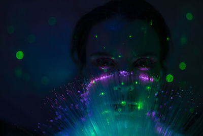 Portrait of beautiful young woman against illuminated background