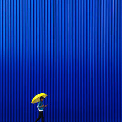Yellow umbrella against blue wall