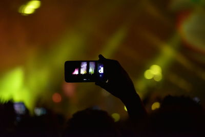 Digital composite image of hand holding smart phone at night