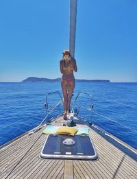 Rear view full length of woman wearing bikini standing in boat on sea