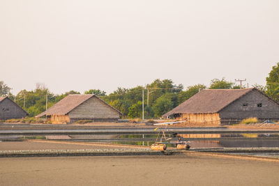 Houses on field by building against clear sky