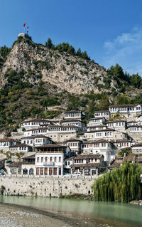 Buildings by river in town against sky