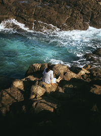 High angle view of people sitting on rock by sea