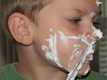 Close-up of boy shaving with razor blade on face