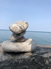 Stack of rocks by sea against clear sky