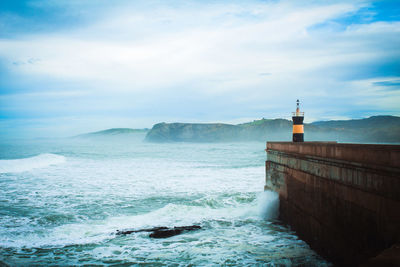 Lighthouse by sea against sky