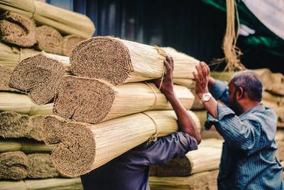 Rear view of men holding stack on wood