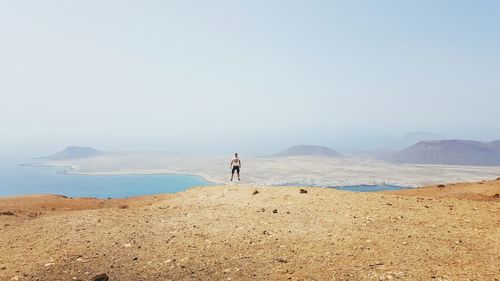 Man levitating over landscape against sky