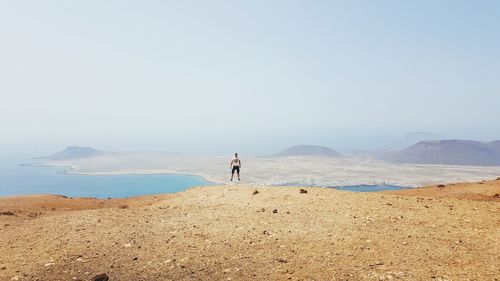 Man levitating over landscape against sky