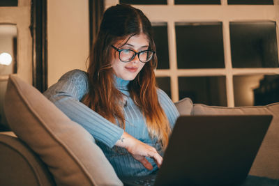 Portrait of young woman using laptop at home