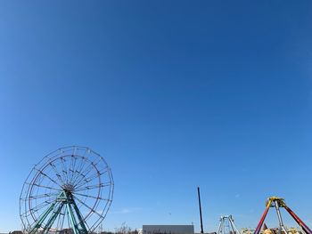 Low angle view of ferris wheel against clear blue sky