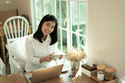 Young woman drinking coffee while sitting at restaurant