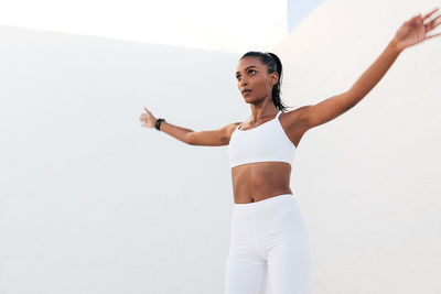Portrait of young woman exercising against white background