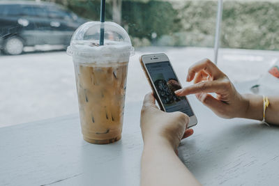 Midsection of man holding mobile phone on table