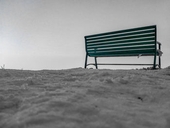 Empty bench on field against sky