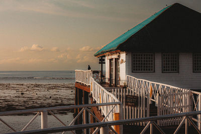 Pier on beach against sky during sunset