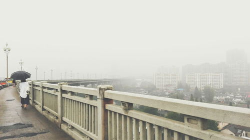 Rear view of woman walking with umbrella on nanjing yangtze river bridge