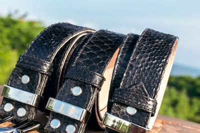 Python skin belts against a background of green trees and blue sky