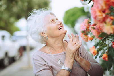 Elderly woman admiring beautiful bushes with colorful roses.